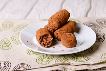 Homemade healthy vegan chocolate truffles with dates, coconut flakes and rolled oats served on white plate
