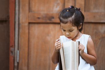Cute asian child girl  opening a book she love to read a book