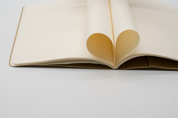 Notebook with pages folded into a heart isolated on white background. Composition of love