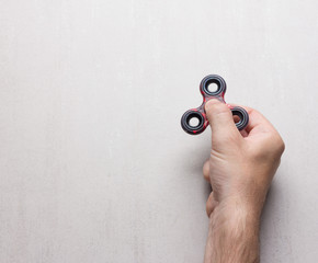 male hand with a popular toy spinner on a gray background with space for text