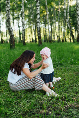 Fototapeta premium Funny mom with baby sitting on the grass