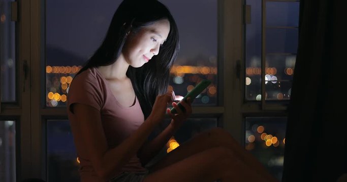 Woman using cellphone at night in home