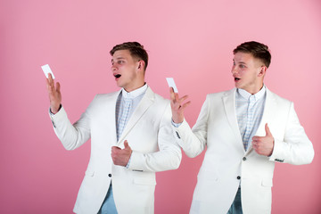 Surprised men reading cards on pink background