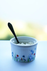 Food. Cottage cheese in a plate and a spoon on a table with a white tablecloth. Healthy food.