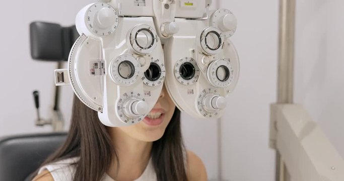 Woman sitting behind phoropter during eye exam