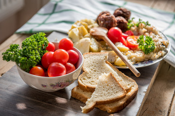 Home prepared meal with meatballs, potatoes, rice, garlic and cherry tomatoes in vintage home style
