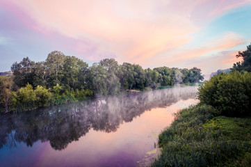 Magnificent sunrise on the river in the summer with fog over the water