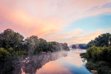 Fototapeta na wymiar Magnificent sunrise on the river in the summer with fog over the water