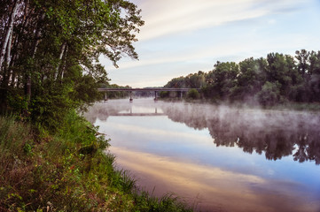 Fototapeta na wymiar A magnificent sunrise on a river with a mist over the water
