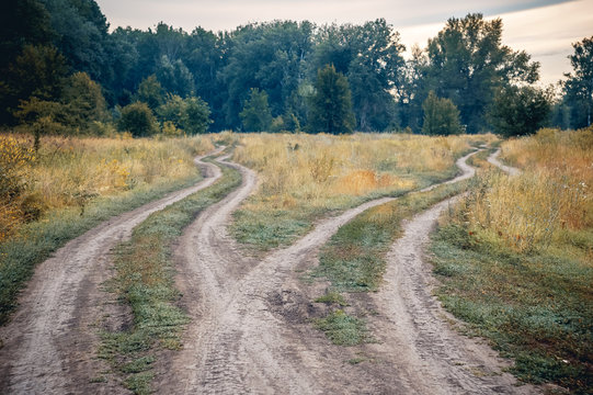 Crossroads, two different directions in the field at summertime. Concept of choose the correct way.