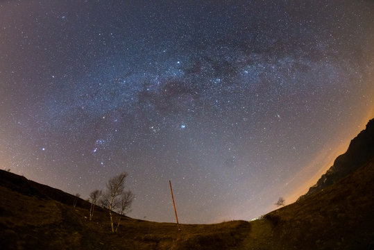 The starry sky and Milky Way captured on the Alps by fisheye lens with scenic distortion and 180 degree view. Andromeda, The Pleiades, Orion and Sirio clearly visible. Low digital noise.