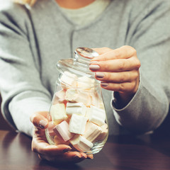 Glass bank with marshmallow in the hands of the seller close-up, toned