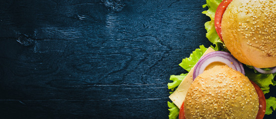 Hamburger with cheese, meat, tomatoes and onions and herbs. On Wooden background. Top view. Free...