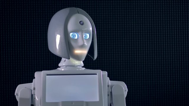 A white robot moves its head and activates indicators for eyes and a mouth. 4K.