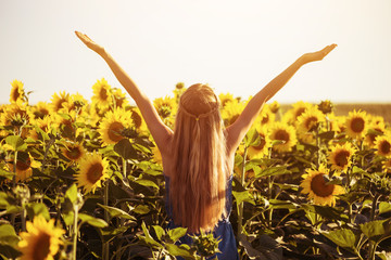 Happy woman enjoys in sunflower field.