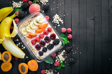 Oatmeal with fresh berries and fruits. Healthy Diet Food. Lunch Boxing. On a wooden background. Top view. Free space for text.