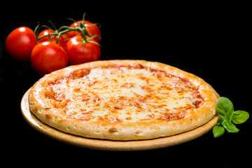 selective focus on classic Italian fresh cheese pizza on wooden round board on dark background,...