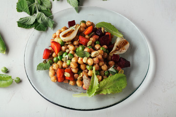 Fresh chickpea salad with mint and vegetables on white rustic background. Healthy lunch concept. Close up, top view