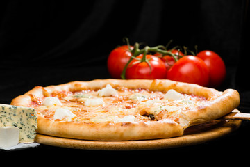 selective focus on sliced piece of appetizing Italian cheese pizza with mozzarella, gorgonzola, emmental and parmesan cheese on dark background
