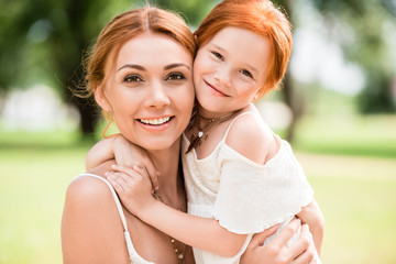 mother and daughter hugging at park