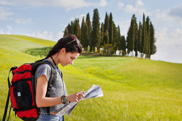 beautiful traveler woman carrying backpack walking on country road.
