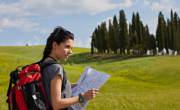 beautiful traveler woman carrying backpack walking on country road.