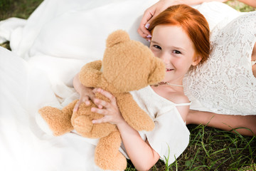 mother and daughter with teddy bear in park