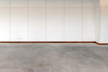 Empty room with concrete flooring and white wooden laminate wall