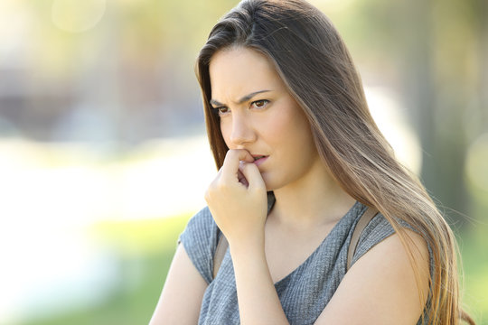 Nervous woman biting nails outdoors