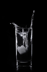A glass of water and ice cube on a black background
