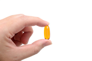 Close up to fish oil capsule in fingers on white background