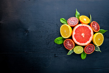 Fresh citrus fruits. Lemon orange, tangerine, lime. On a black background Wooden. Top view.