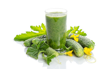  glass with green smoothie and  cucumbers, flowers, leaves isolated on white