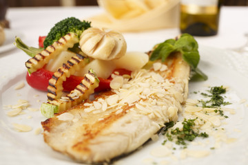Hake fillet with grilled vegetables arranged on a plate, Traditional dish in elegant setting, Selective focus with soft light