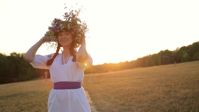 Girl walking in meadow wearing flower circlet and ethnic outfit at sunset in nature.