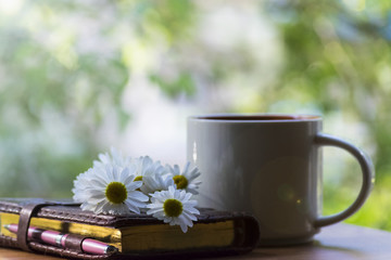 Mug, daisies, Notepad, glasses. The concept of a Sunny summer morning.