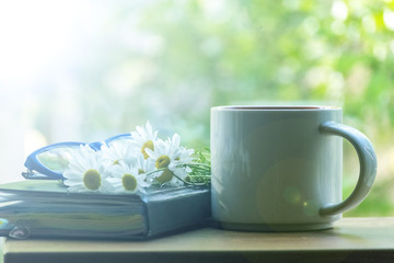 Mug, daisies, Notepad, glasses. The concept of a Sunny summer morning.