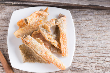 Crispy fried salmon skin on wood background