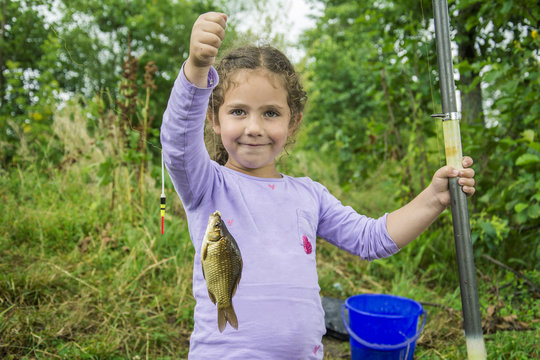 In the summer on a fishing little girl caught a large carp.