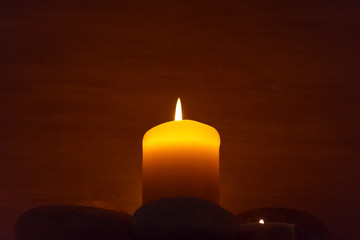 A candle is lit and surrounded by stones.