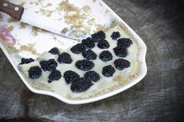 Dessert with blackberries in a plate with knife isolated on wooden background