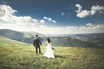 Fototapeta premium Beautiful gorgeous bride posing to groom and having fun, luxury ceremony at mountains with amazing view, space for text, wedding couple