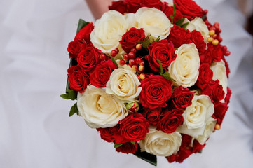 Wedding flowers, a bouquet of red and cream roses with red berries. The bride's bouquet
