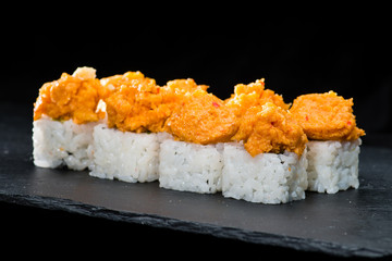 Traditional Japanese cuisine.  Selective focus on sushi rolls and breaded pieces of shrimp on dark background