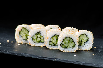 Traditional Japanese cuisine.  Selective focus on sushi rolls with cucumber, cream cheese, rice, sesame seeds on dark background