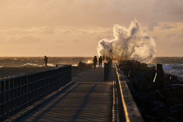 wave hits the pier at sunset in nr. Vorupoer at the North Sea Coast in Denmark