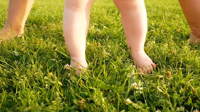 small baby's cute feet on the summer green grass. Full HD slow motion video