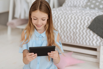Cute little lady beaming while playing on tablet computer