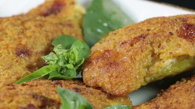 Crocchette di zucchine e mollica di pane con basilico fresco in un piatto rotante.