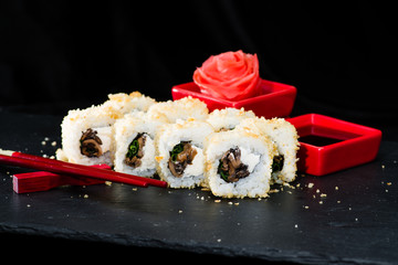 Traditional Japanese cuisine.  Sushi rolls with rice, green onion, champignon mushrooms and soy sauce on dark background